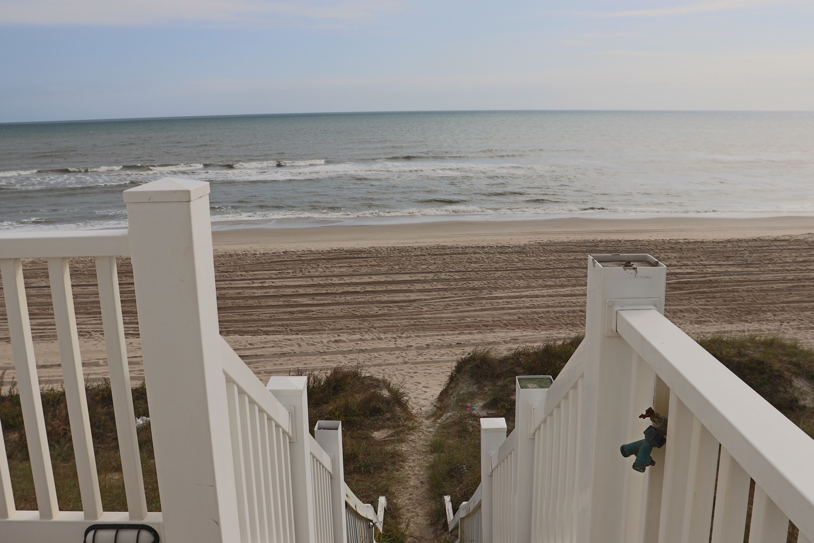 White stairs leading directly to pristine sandy beach and rolling ocean waves - your perfect seaside escape.