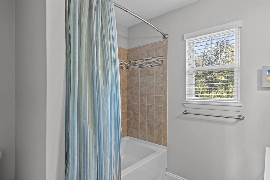 Fresh natural light streams through the window as you unwind in your spacious tiled bathroom with convenient grab bars.