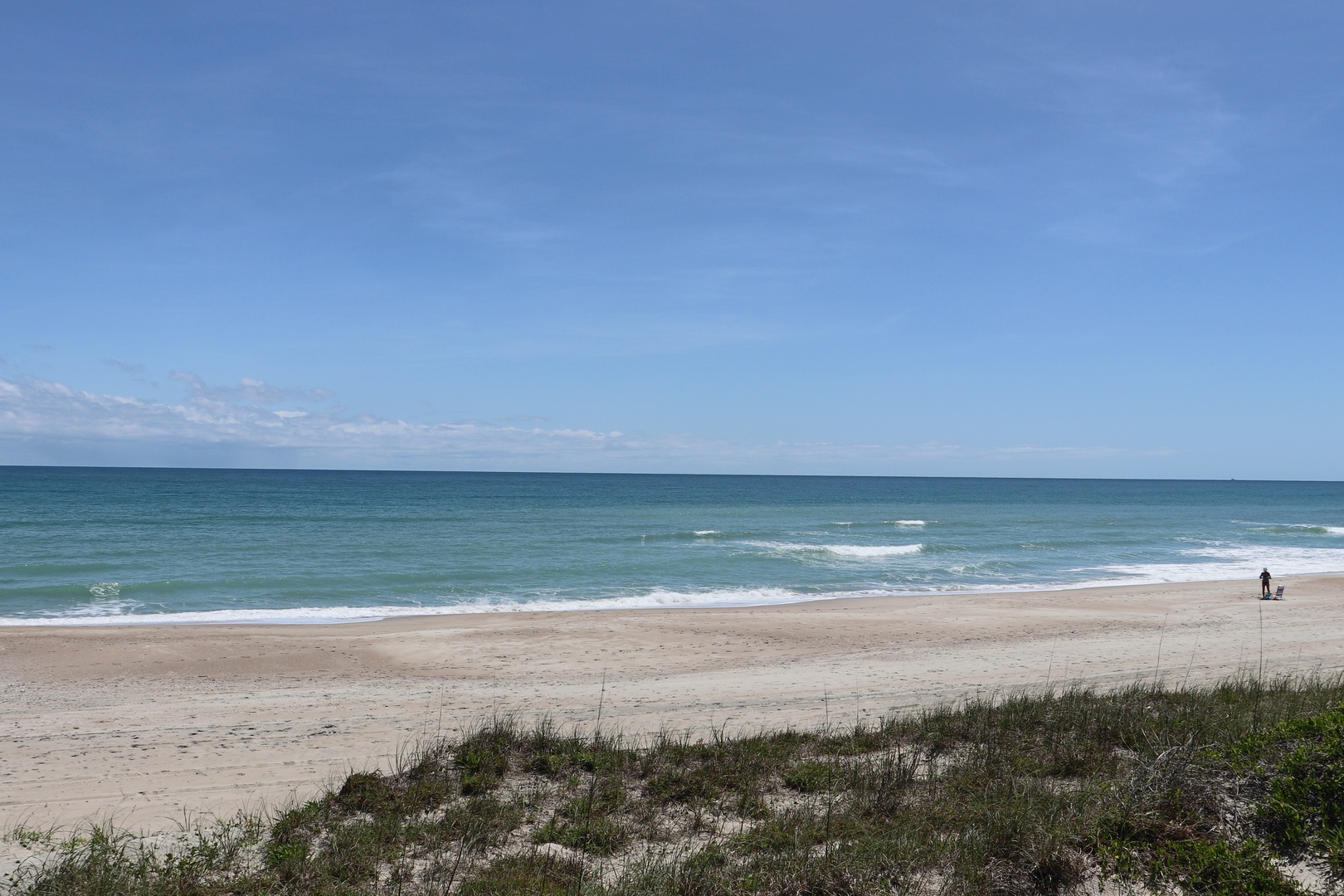 Pristine beach stretch with rolling waves and endless blue horizon, perfect for peaceful coastal getaways.