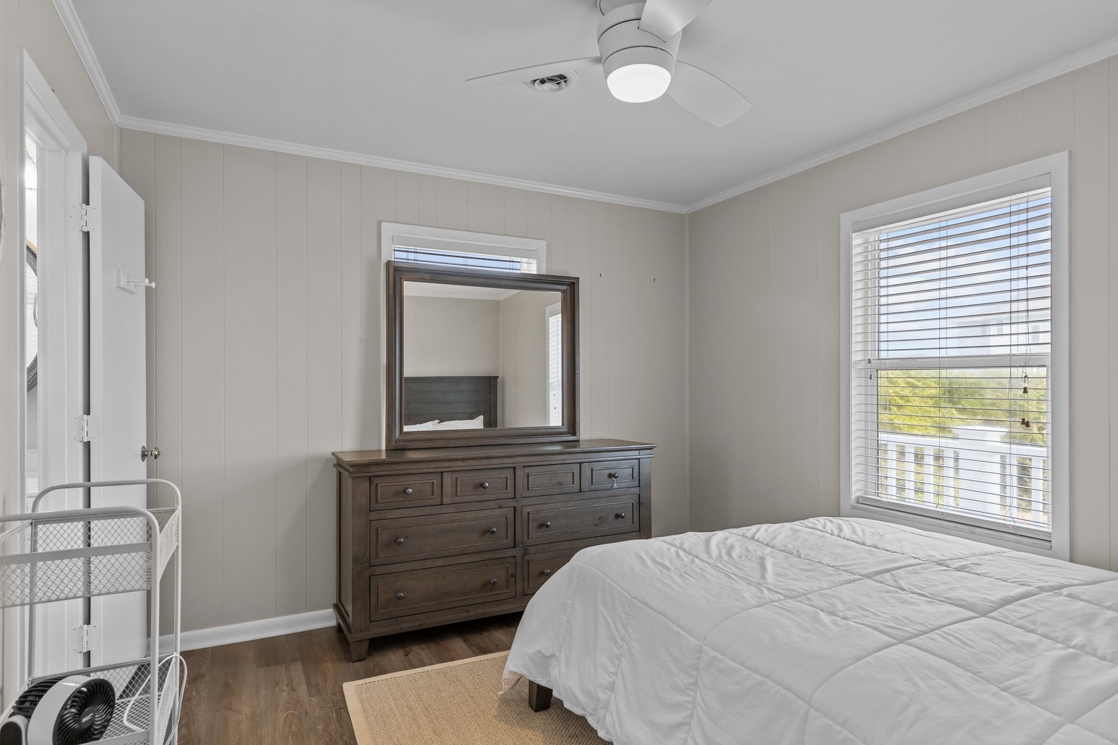 Drift off to sleep in this peaceful bedroom featuring crisp white linens and thoughtful touches like the ceiling fan for your comfort.