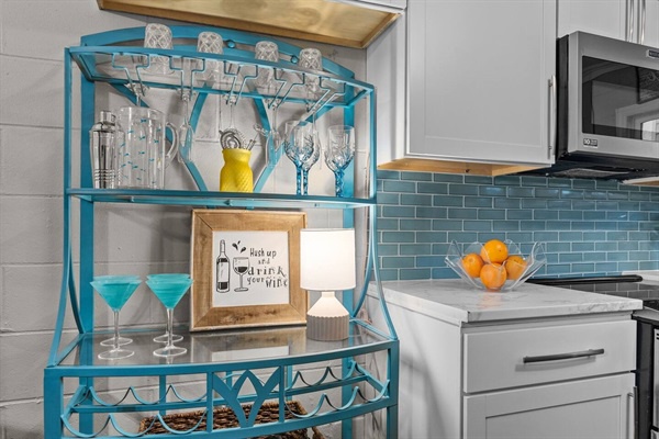 Your stylish bar cart awaits cocktail hour, featuring elegant glassware and coastal charm in your bright kitchen space.