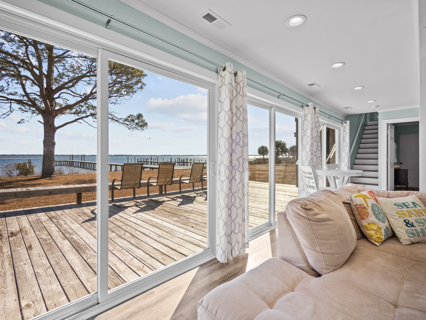 Relax on your plush sofa while floor-to-ceiling windows frame stunning waterfront views, connecting you to your private deck and peaceful bay setting.