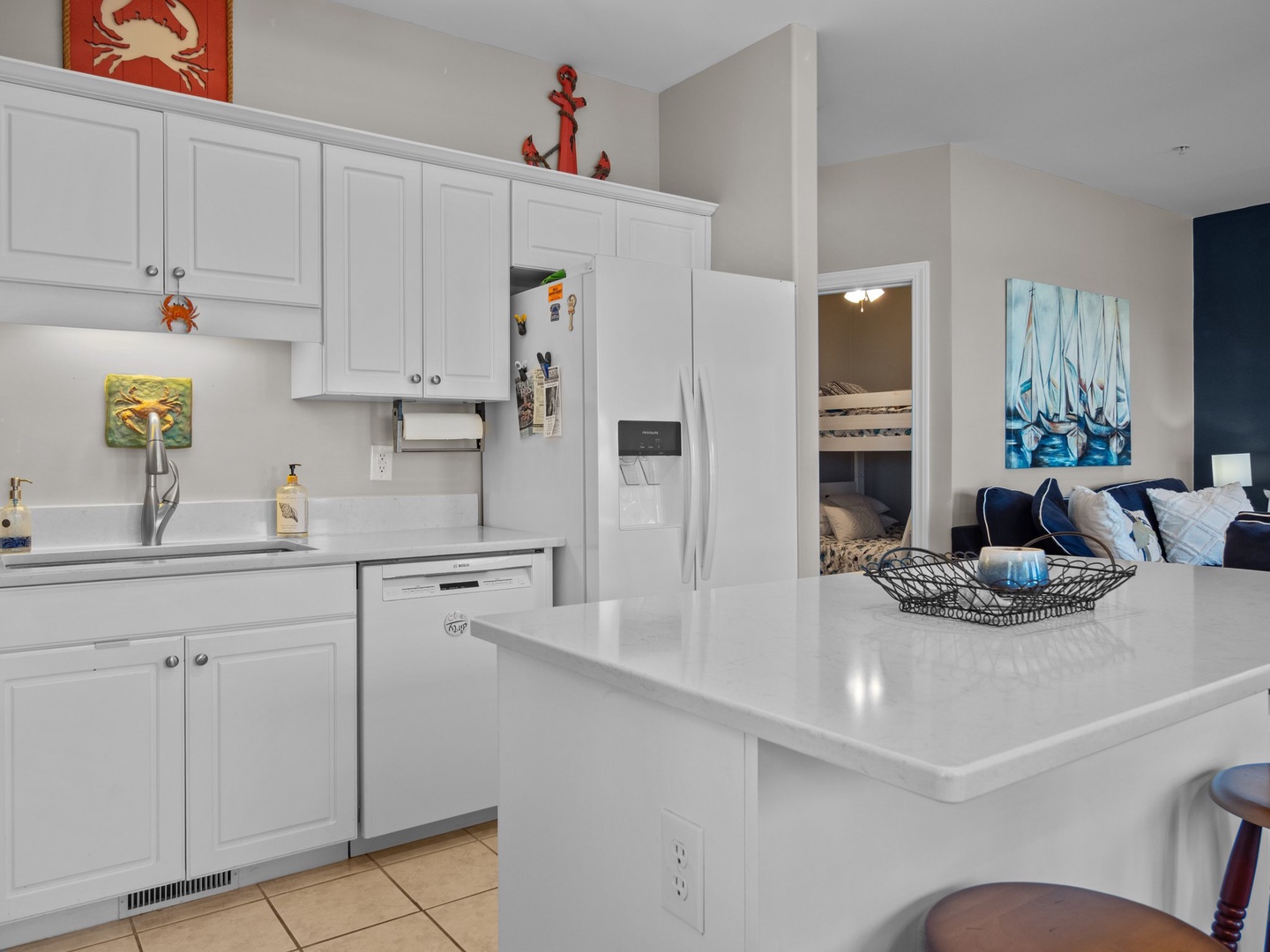 Your coastal-themed kitchen gleams with white cabinets and counters, perfect for preparing meals while enjoying ocean views.