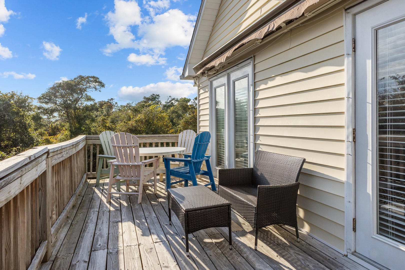 Step onto your private deck where colorful Adirondack chairs and cozy seating await among treetops under endless blue skies.