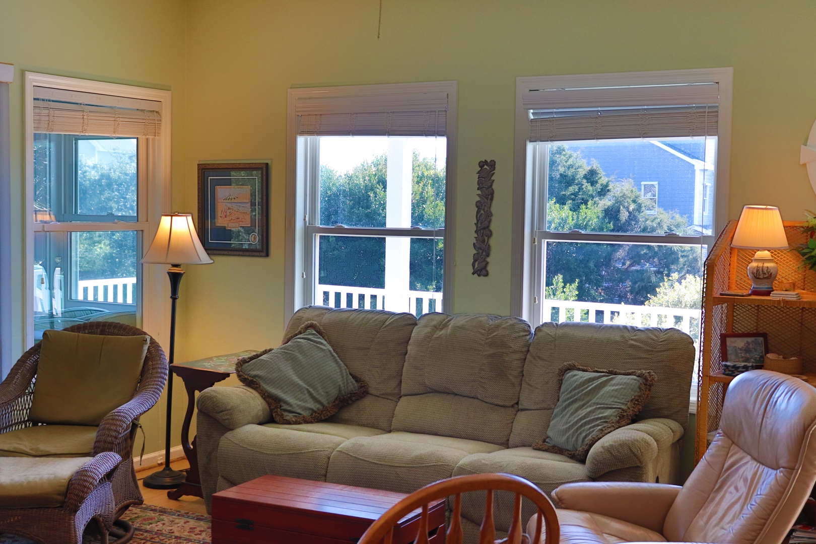 Relax in your comfortable living room with soft lighting and peaceful views of lush greenery through bamboo-shaded windows.