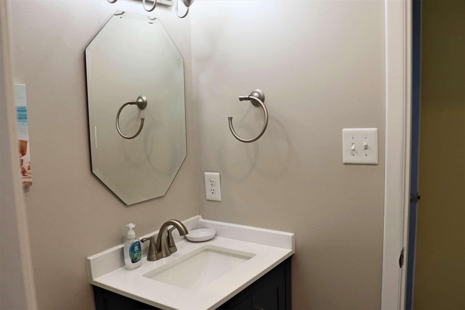 Your private bathroom features a stylish vanity with quartz countertop, elegant octagonal mirror, and thoughtful amenities for your comfort.