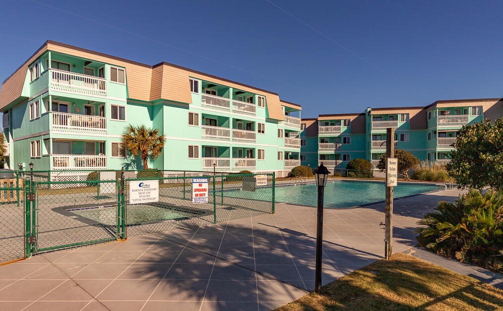 Oceanfront resort buildings with swimming pool and tennis court create the perfect vacation setting under clear blue skies.