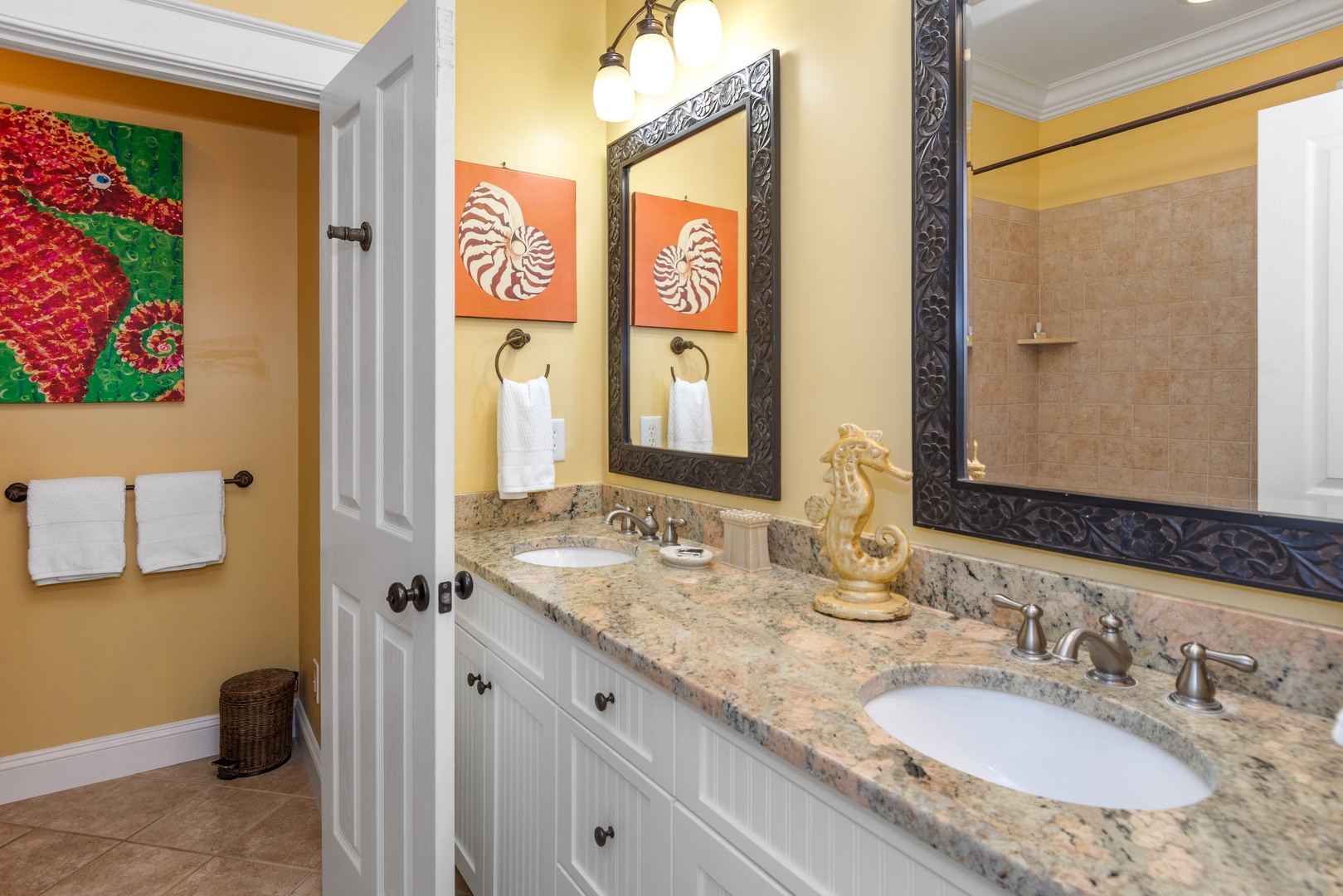 Your elegant dual-sink bathroom features granite countertops, tropical artwork, and plush towels for a spa-like morning routine.