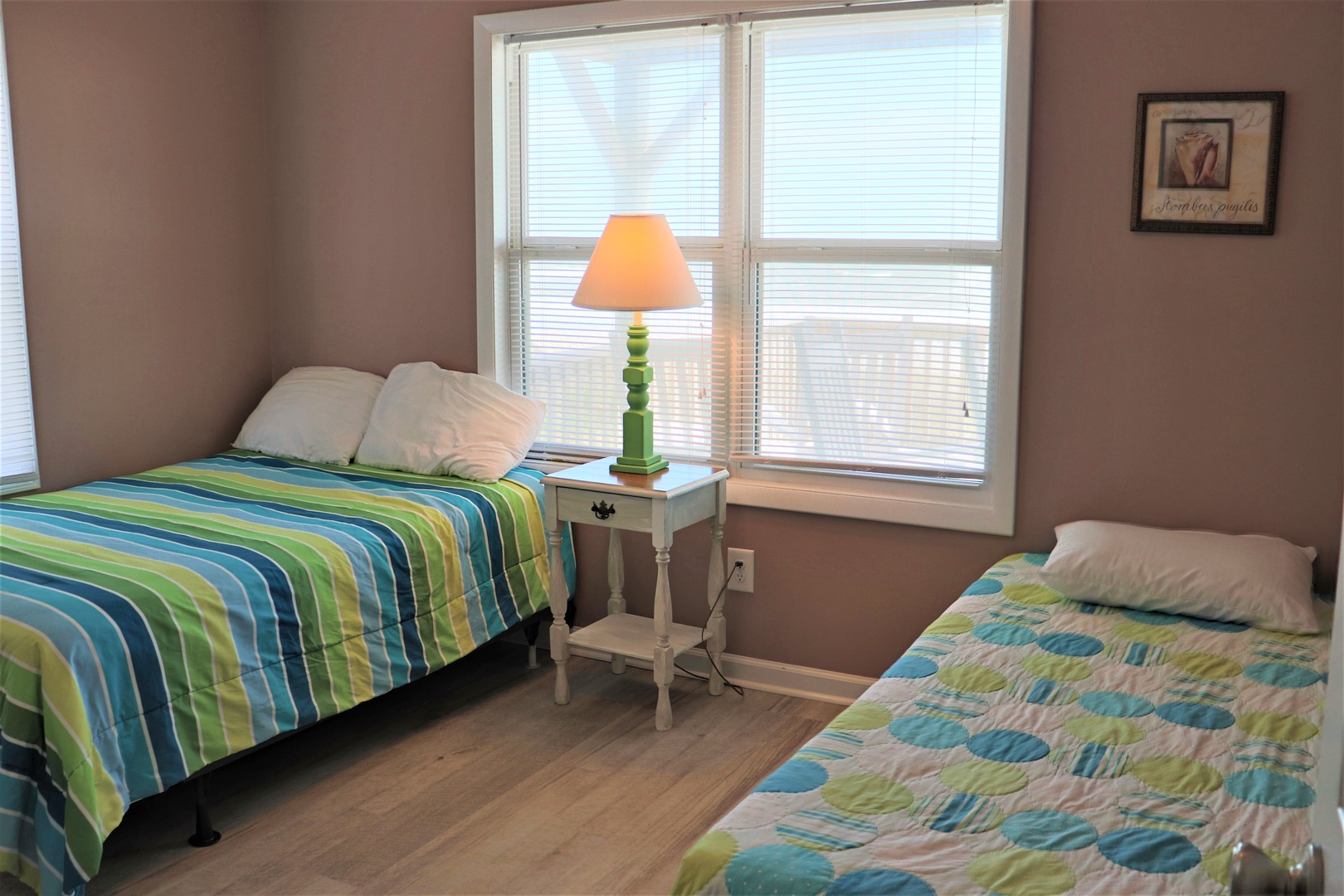 Rest comfortably in your bright bedroom featuring twin beds with cheerful linens and warm natural light streaming through large windows.