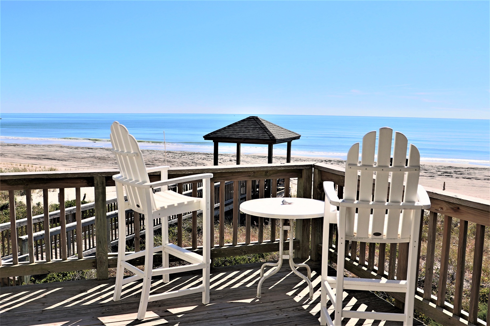 Beachfront deck with panoramic ocean views and classic Adirondack chairs for morning coffee or sunset cocktails.