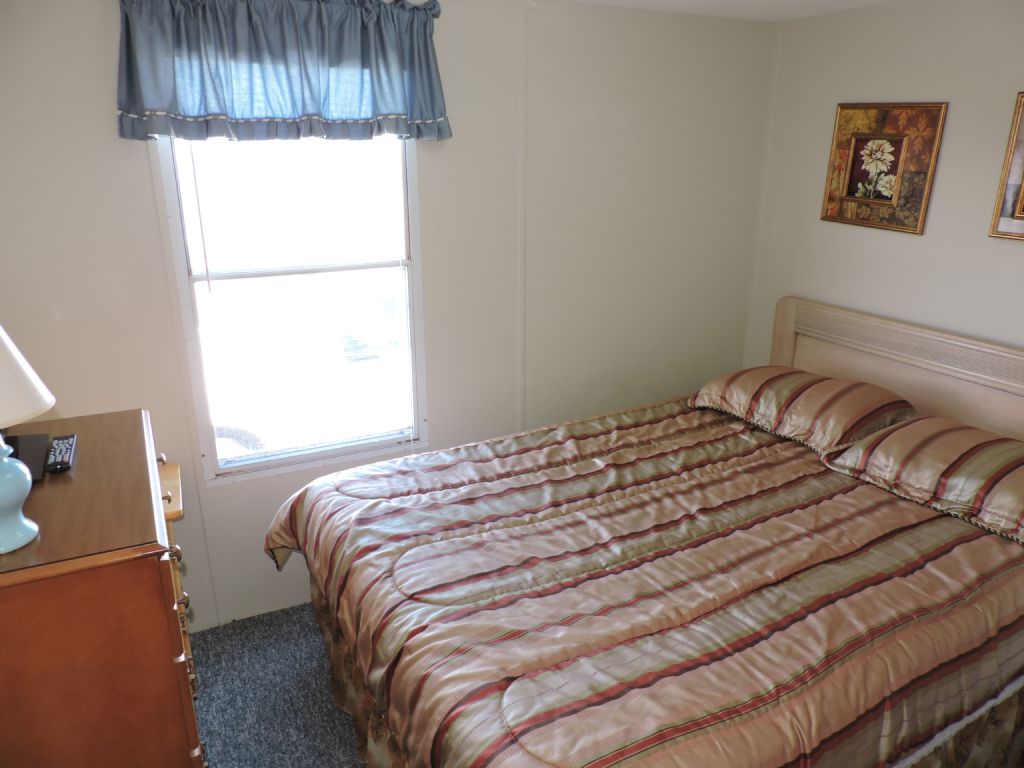 Your cozy bedroom features a comfortable bed with cheerful striped linens, letting in natural light through your window.