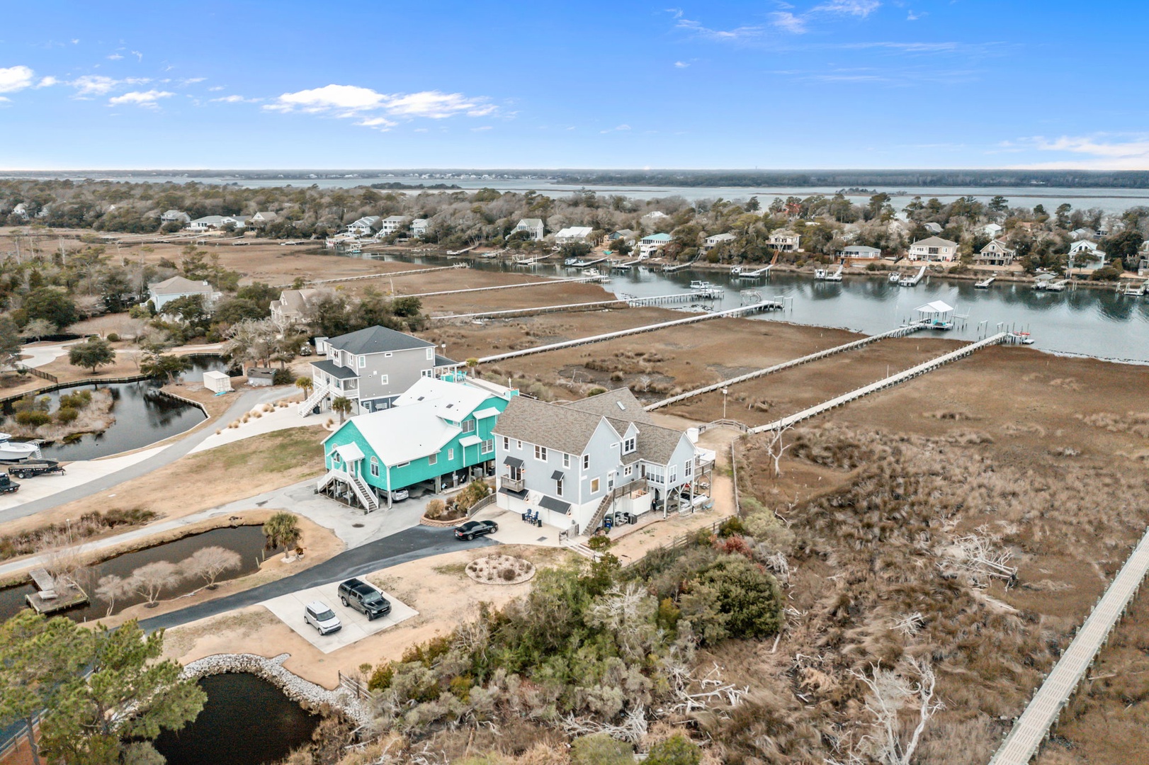 Aerial view of waterfront vacation homes nestled along the coastline with marina access and natural surroundings.