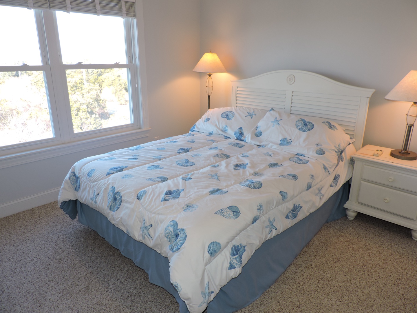 Drift off to sleep surrounded by coastal charm in your bright bedroom, where sea-shell bedding and warm lamplight create the perfect retreat.