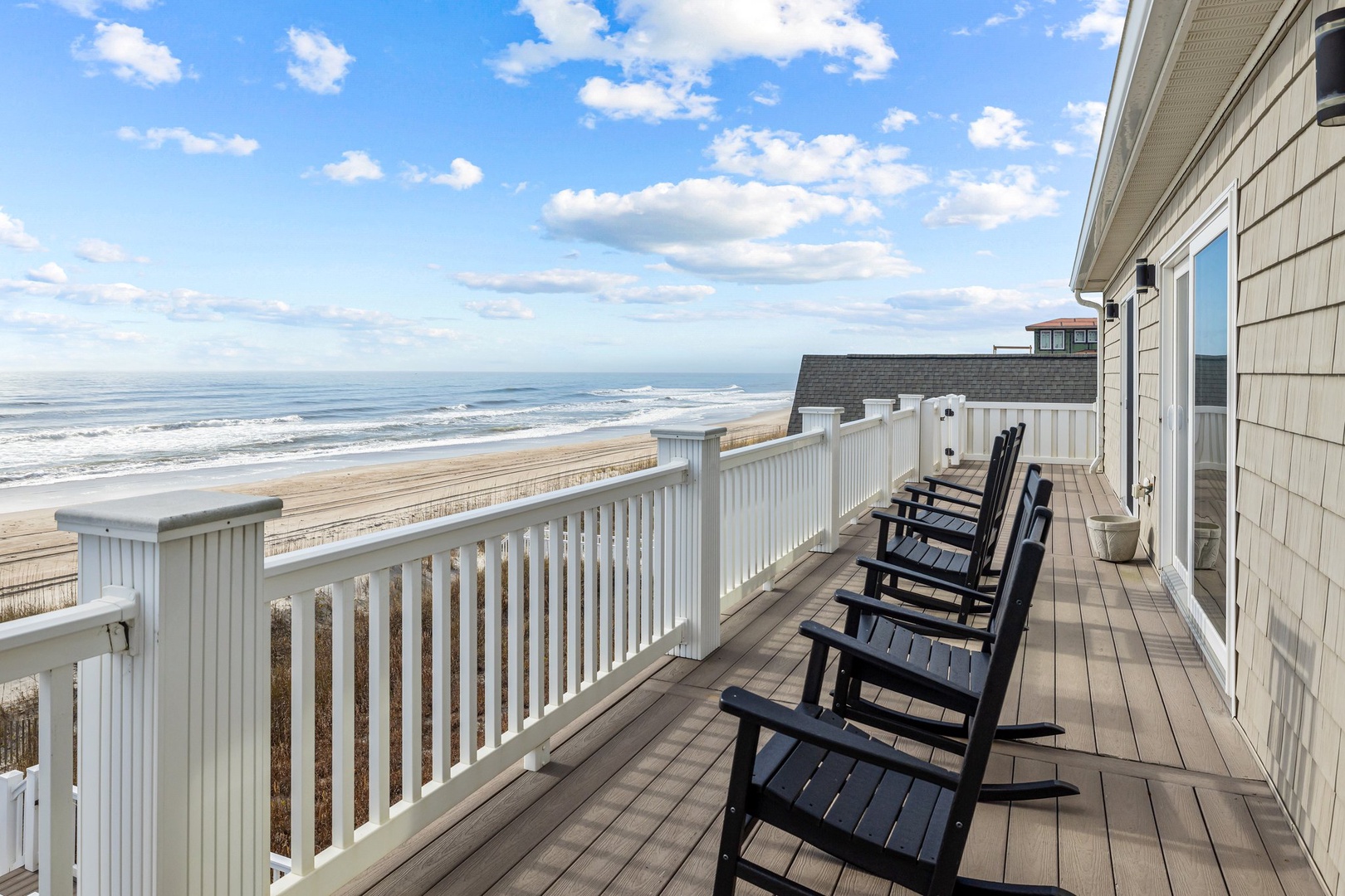Spacious oceanfront deck with comfortable seating offering direct beach access and stunning ocean views for your perfect coastal getaway.