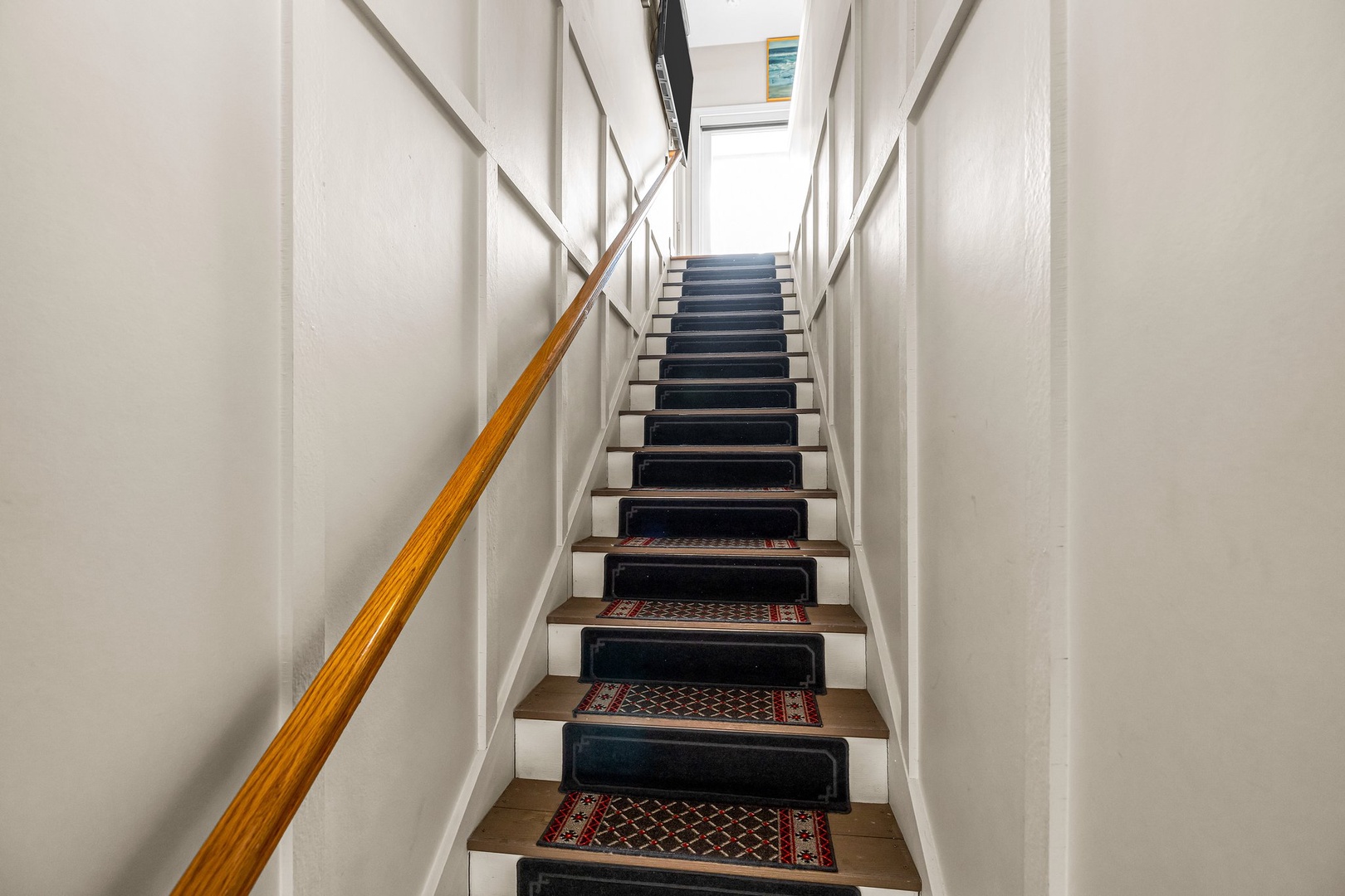 Climb these elegant carpeted stairs to reach your private retreat, with warm wood railings guiding your way upward.