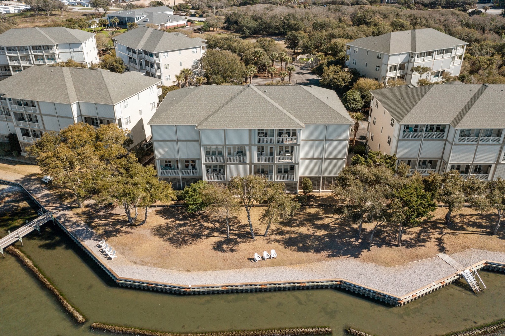 Waterfront vacation rental complex with private beach access and multiple buildings nestled among coastal trees.