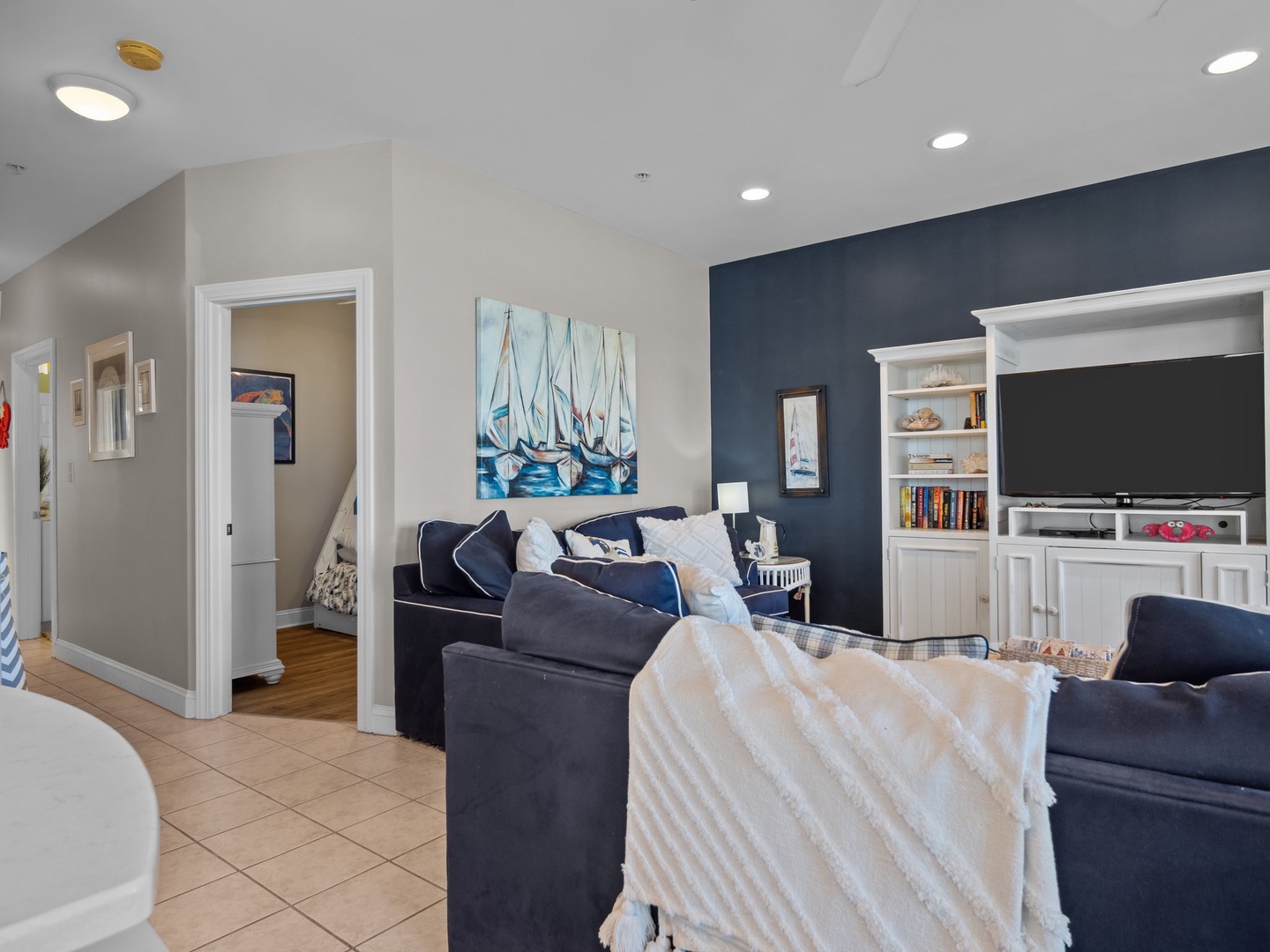 Unwind in your coastal-inspired living room, where nautical artwork and plush navy seating create the perfect spot for movie nights together.