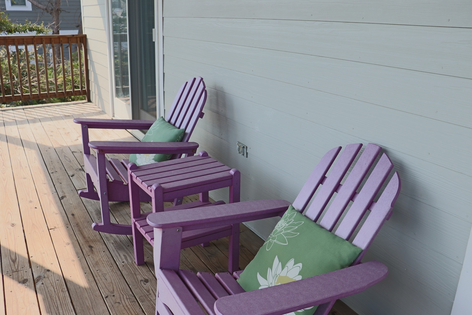 Unwind on your private deck with two purple Adirondack chairs and matching footrests, complete with soft green cushions for ultimate relaxation.