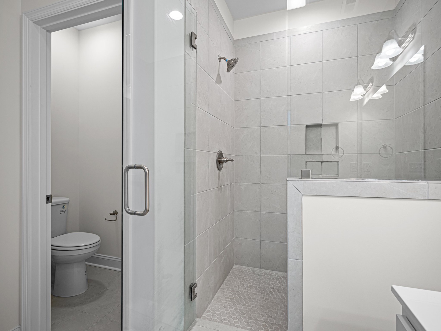 Step into your pristine spa-like bathroom featuring elegant marble tiles, rainfall shower, and modern amenities designed for your comfort.