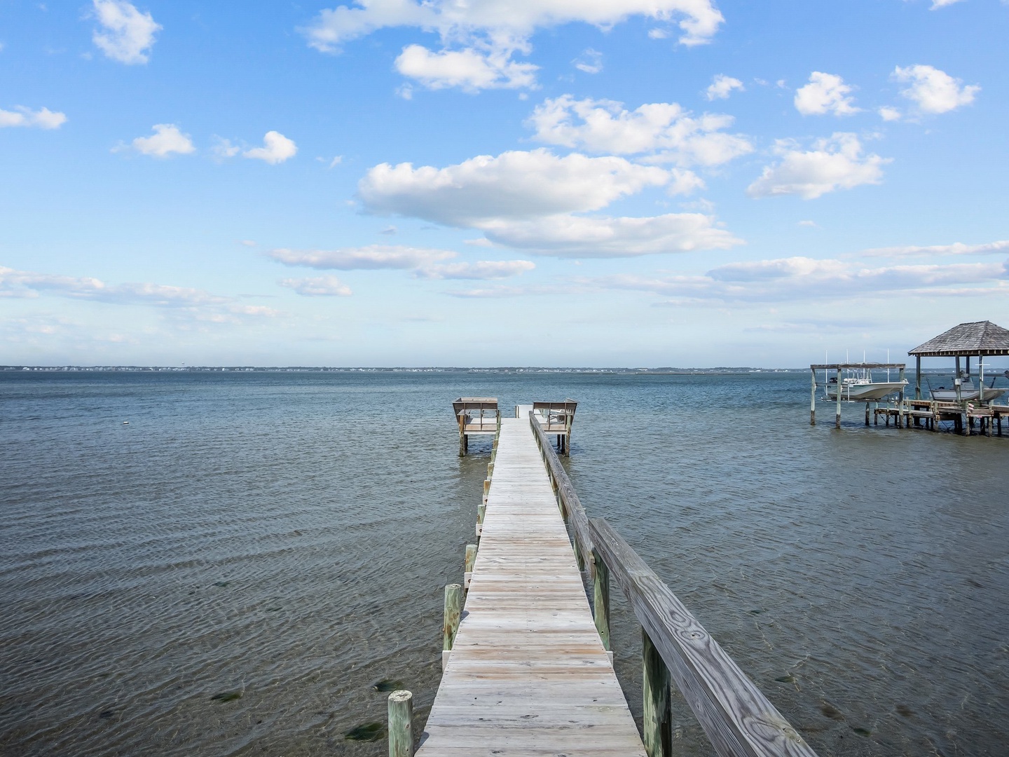 Private waterfront dock extends into calm waters, offering direct access to the bay with covered pavilion nearby.