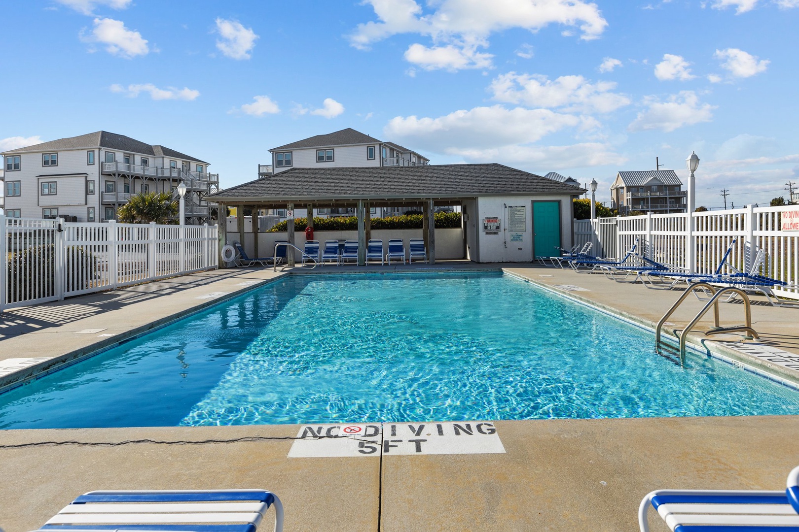 Sparkling community pool surrounded by comfortable lounge chairs where you can soak up the sun and cool off after beach days.