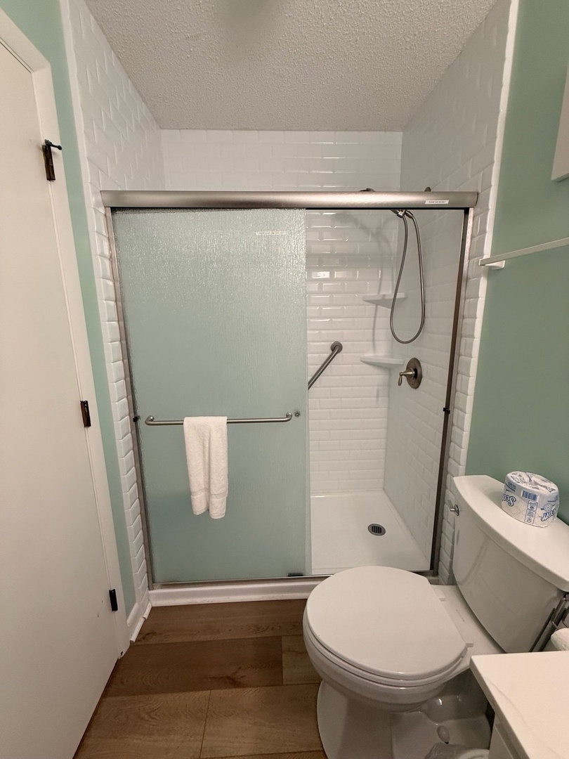 Freshen up in your bright, modern bathroom with a spacious walk-in shower wrapped in gleaming white subway tile. The frosted glass door and gleaming fixtures make every rinse feel like a mini-spa moment.