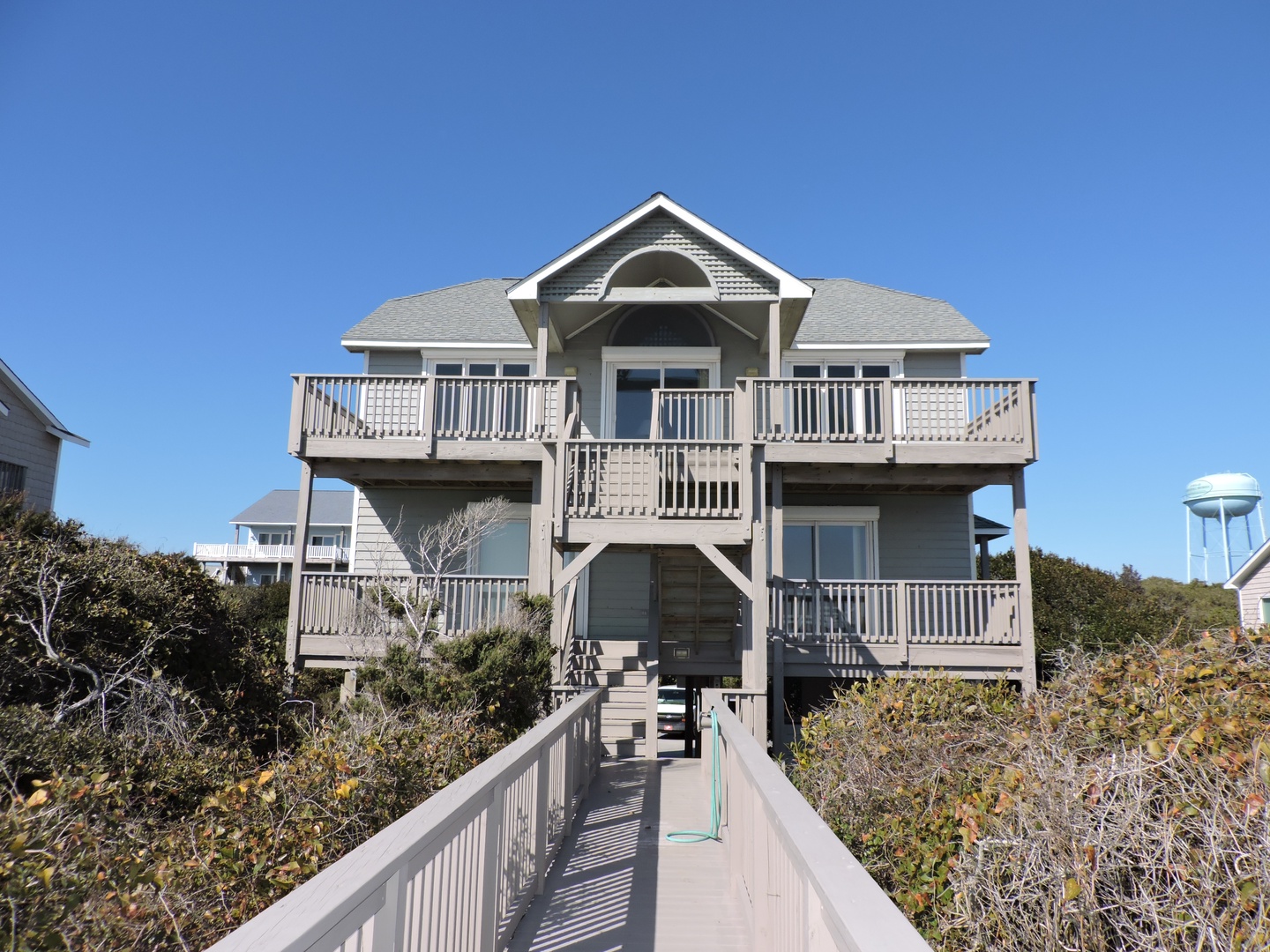 Beachfront vacation home with multiple levels of wraparound decks overlooking the ocean. Elevated design provides stunning coastal views and beach access.