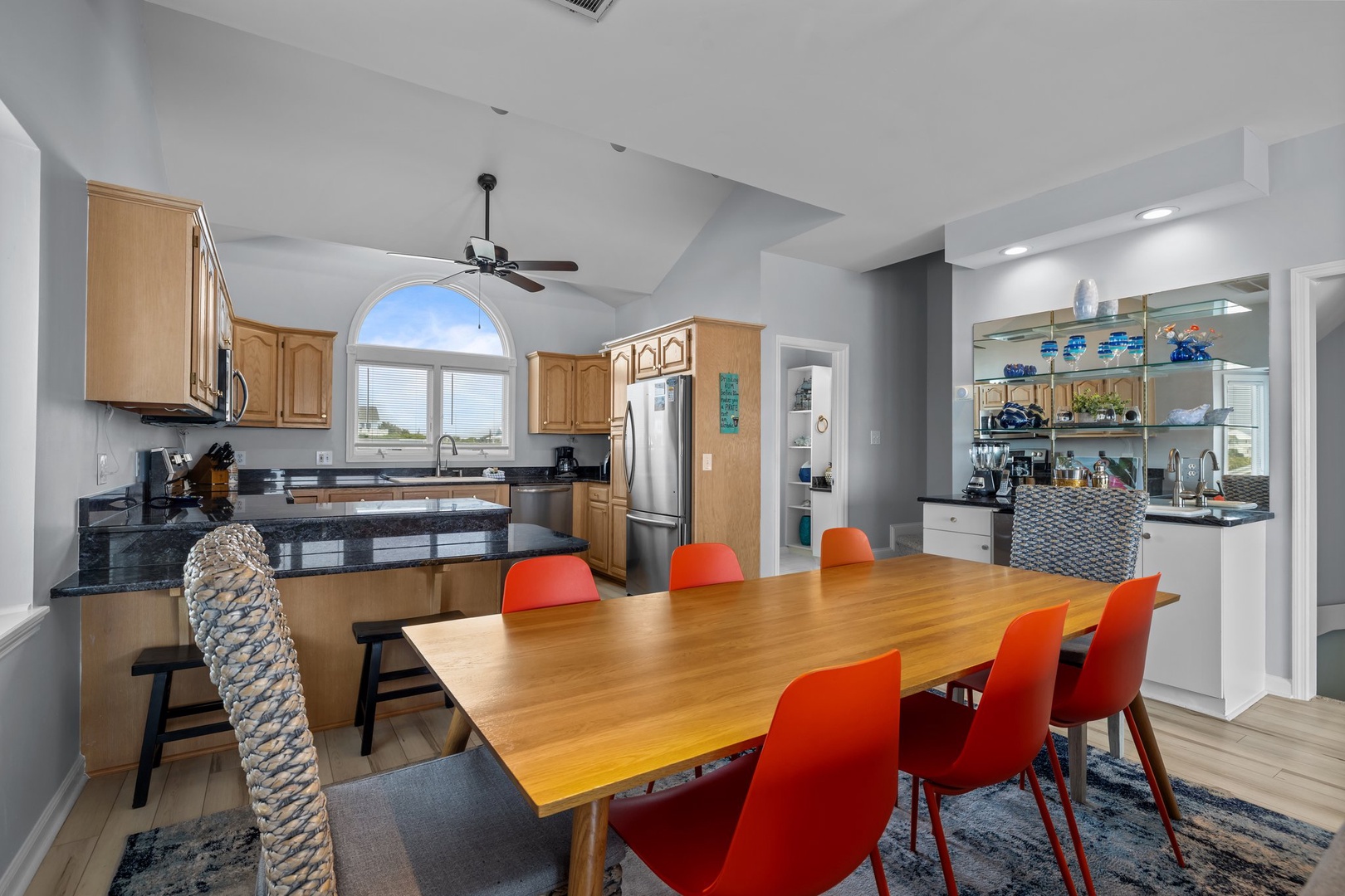 Your open-concept kitchen flows seamlessly into the dining area, where vibrant orange chairs invite memorable meals together.