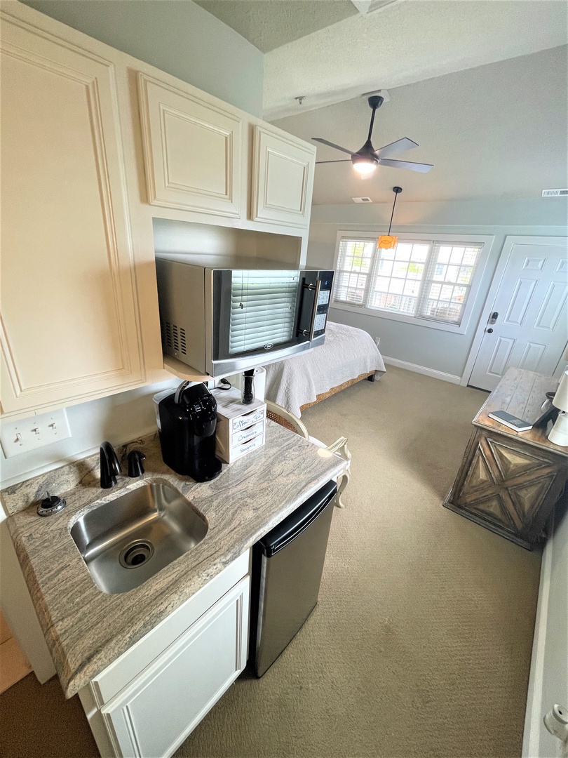 Your bright studio features white cabinets, granite counters, stainless appliances, and a cozy bedroom area with natural light.