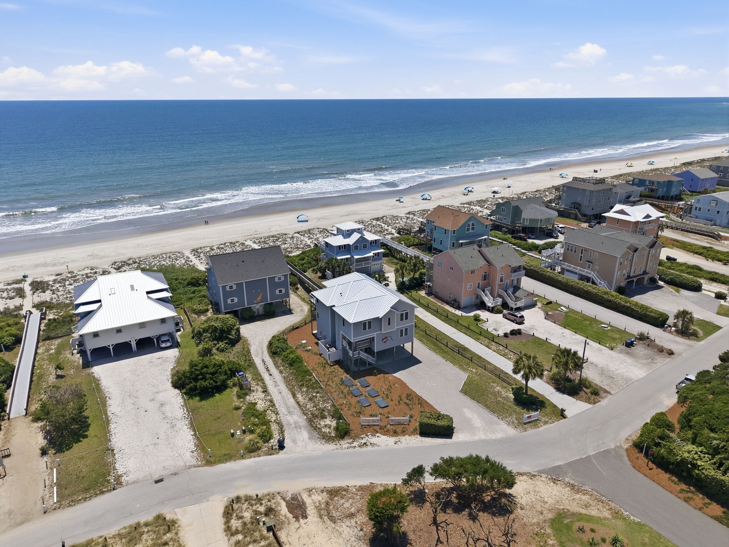 Coastal neighborhood with beachfront vacation homes along a pristine sandy shore, offering easy access to the ocean and a peaceful seaside setting for a relaxing getaway.