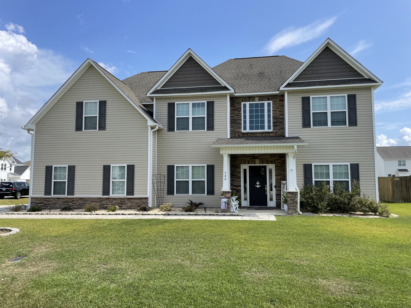 Spacious two-story home with stone accents and welcoming front porch in a peaceful residential neighborhood.