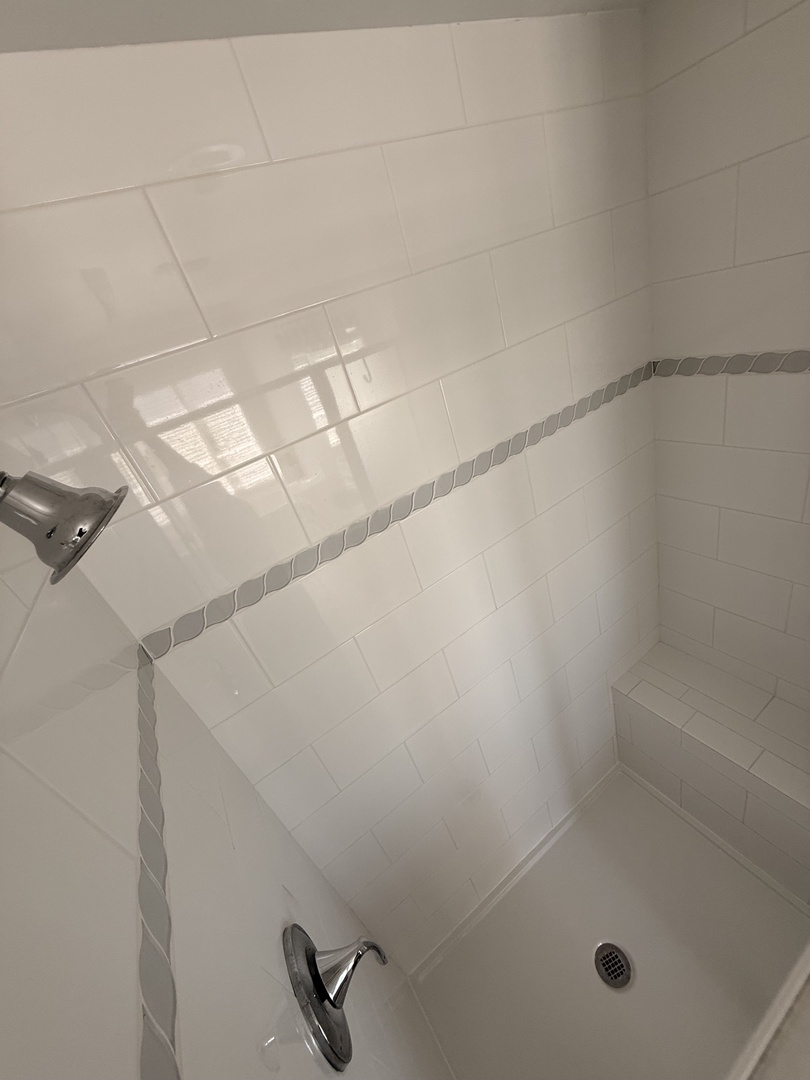 Bright, pristine walk-in shower with sleek tiling and modern fixtures—your refreshing retreat after a day exploring the area.