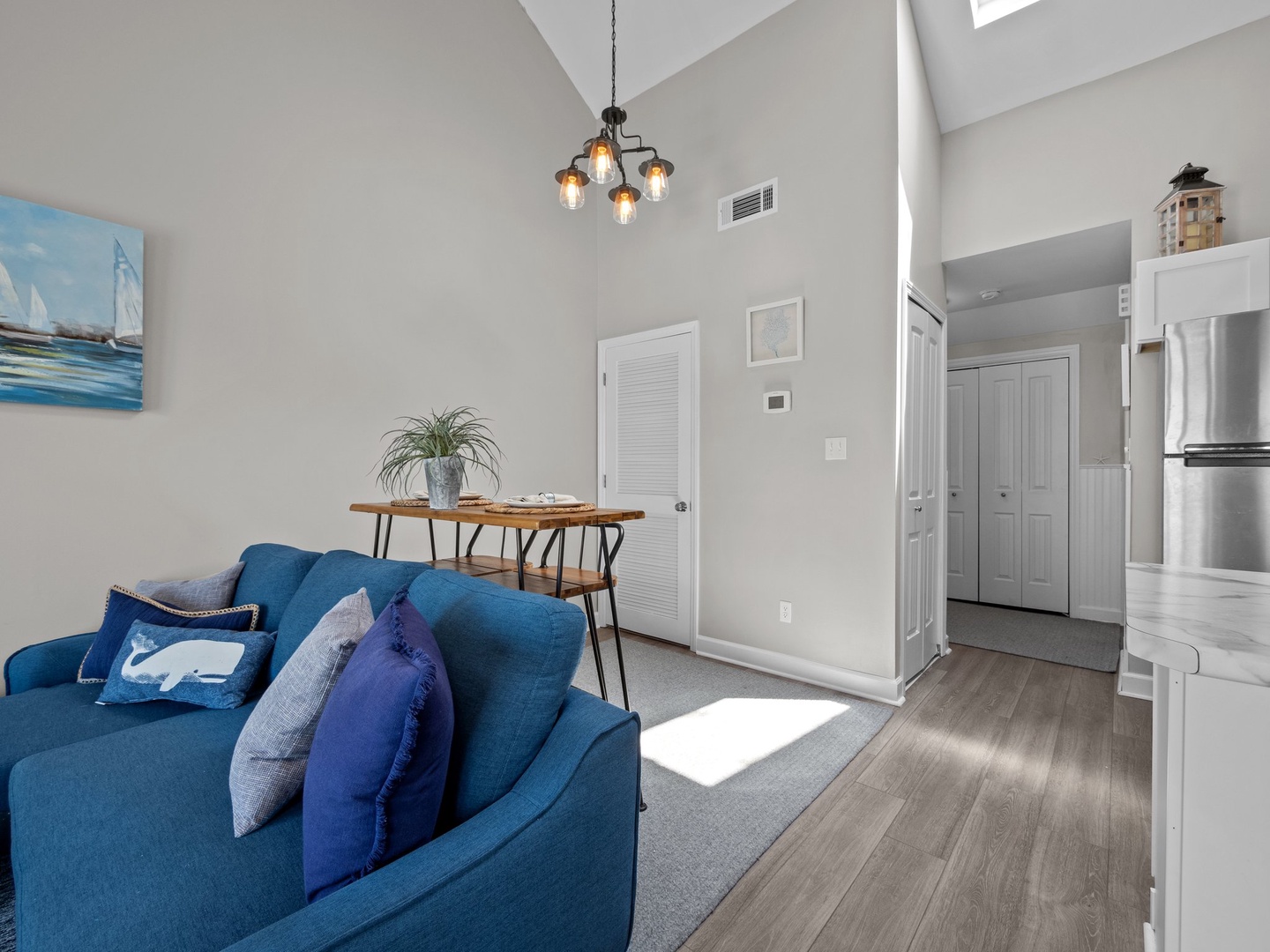 Relax in your bright living space with soaring ceilings, stylish blue furnishings, and warm pendant lighting creating the perfect atmosphere.