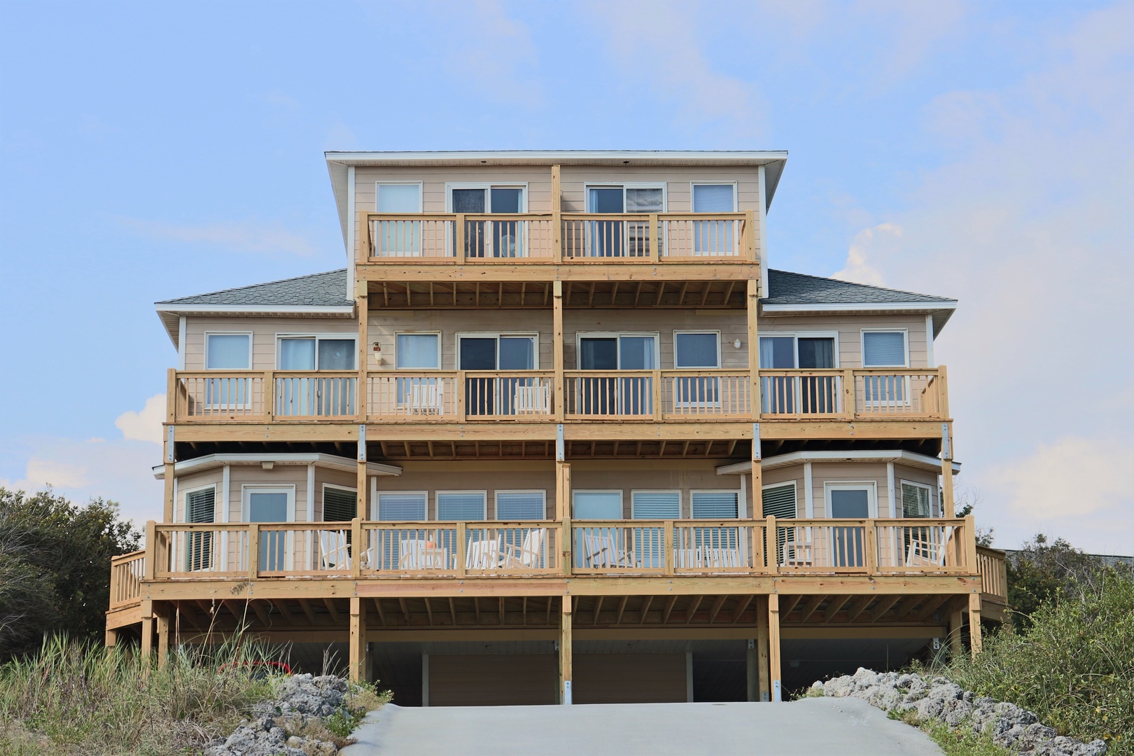 Multi-level beachfront vacation home featuring wraparound decks and elevated coastal architecture surrounded by natural dune vegetation.