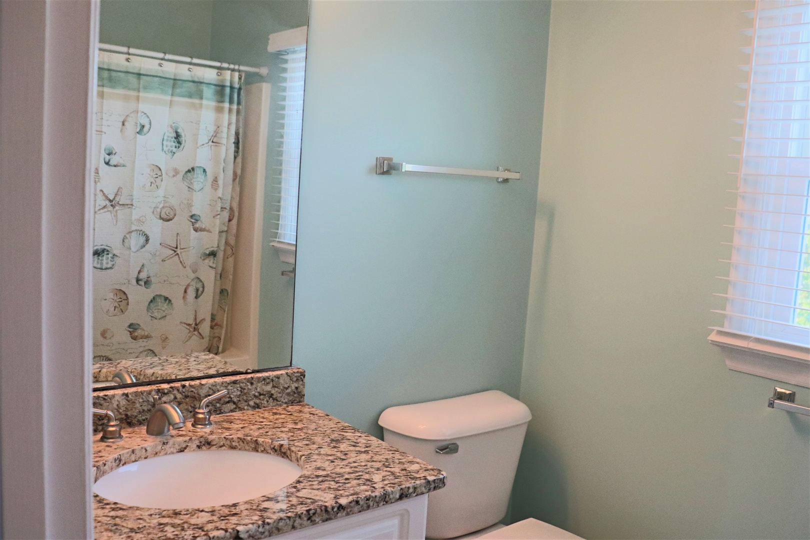 Your private bathroom features granite countertops, coastal-themed shower curtain, and natural light for your morning routine.