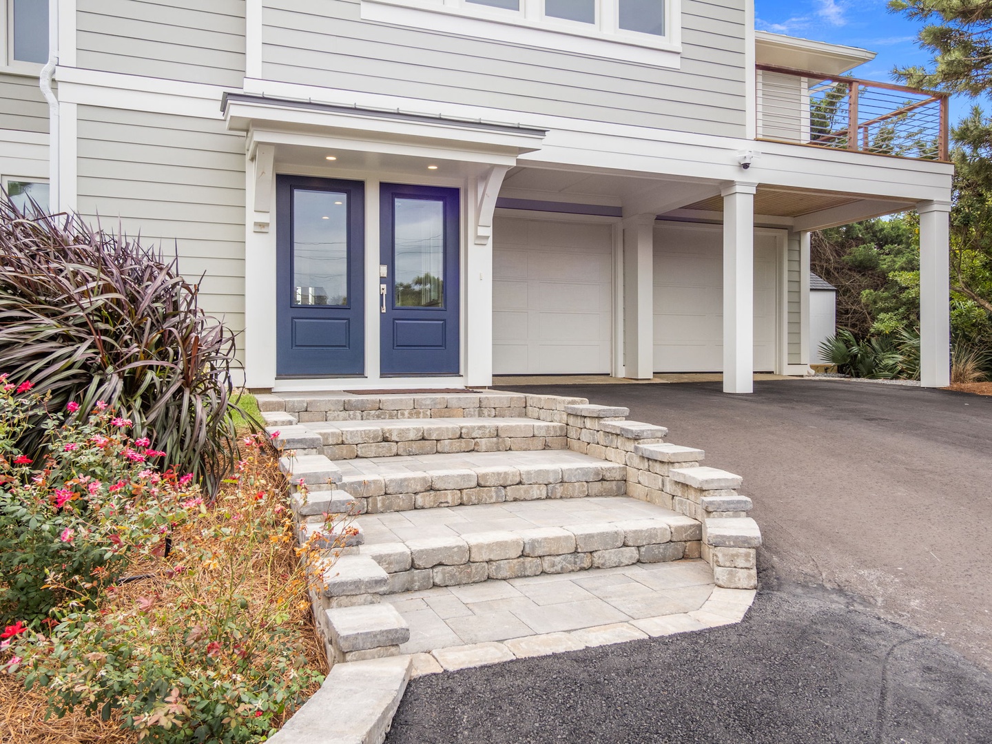 Modern coastal property featuring a welcoming entrance with covered parking and beautifully landscaped grounds surrounded by lush greenery.