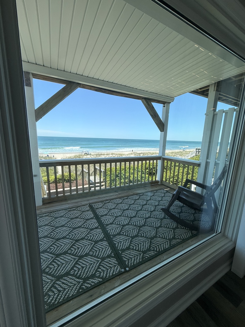 Peek through to your private balcony with a patterned seating area, ocean views, and a lattice shade screen for sunny mornings or tranquil evenings.