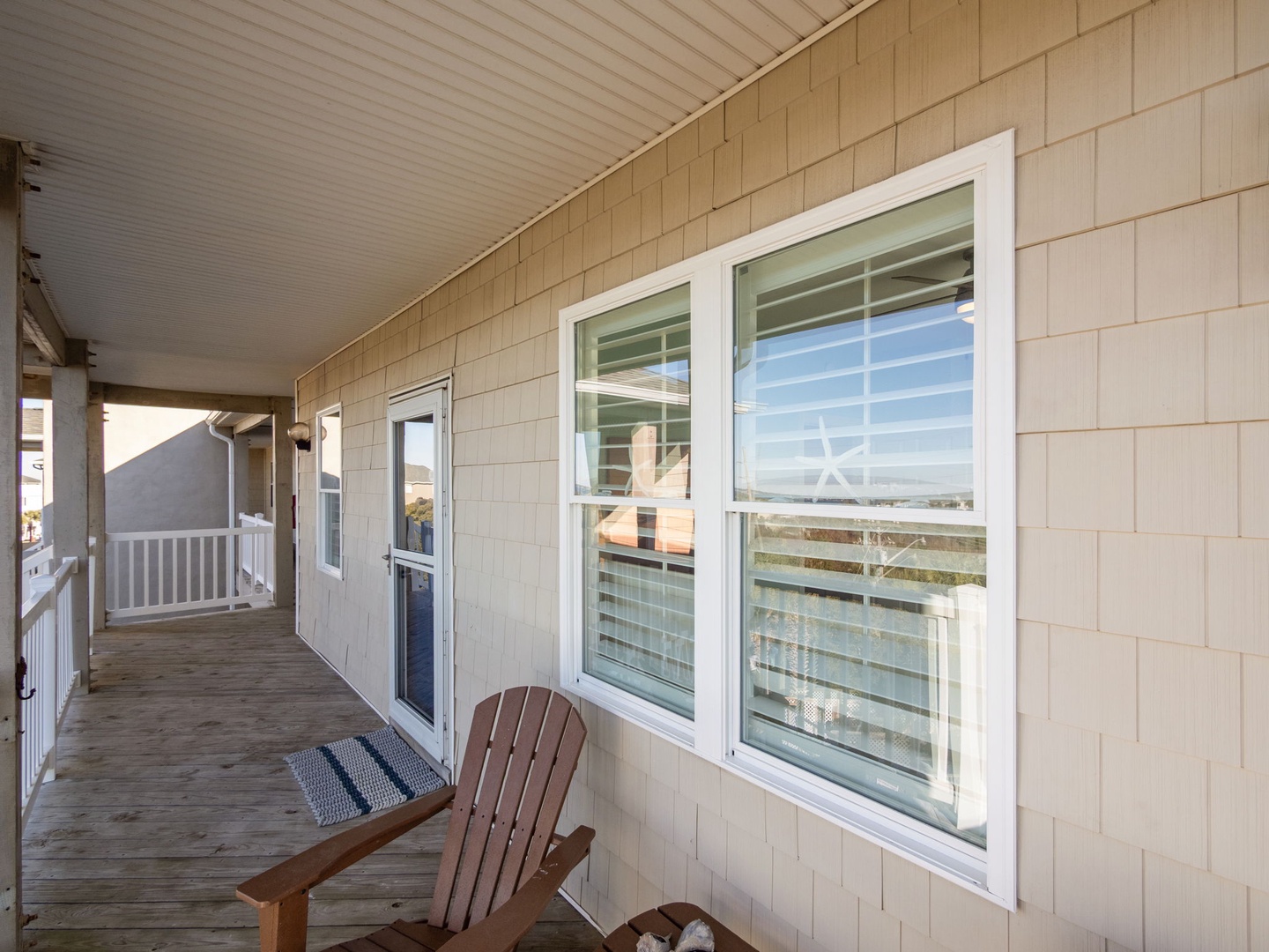 Your private covered porch offers peaceful seating with an Adirondack chair where you can unwind while enjoying scenic views through the large windows.