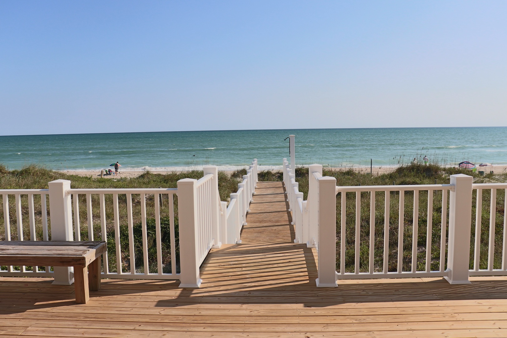 Private boardwalk leads directly to pristine sandy shores where turquoise waters meet endless blue skies.