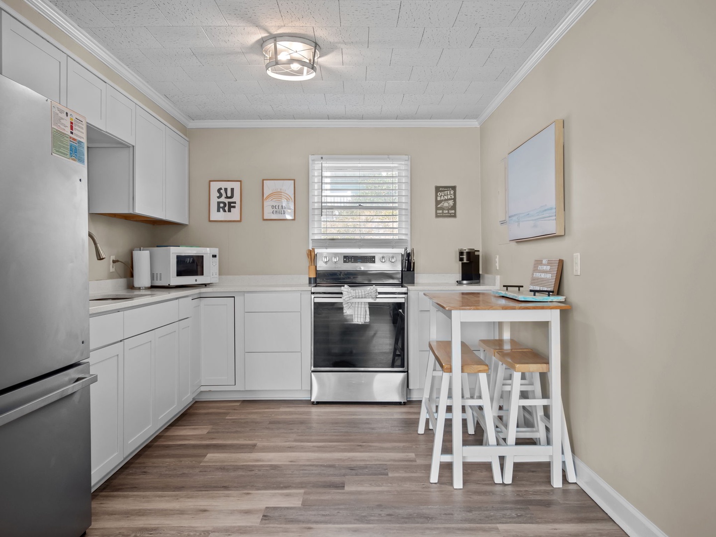 Your fully equipped kitchen features modern appliances and charming coastal artwork, perfect for preparing meals during your stay.