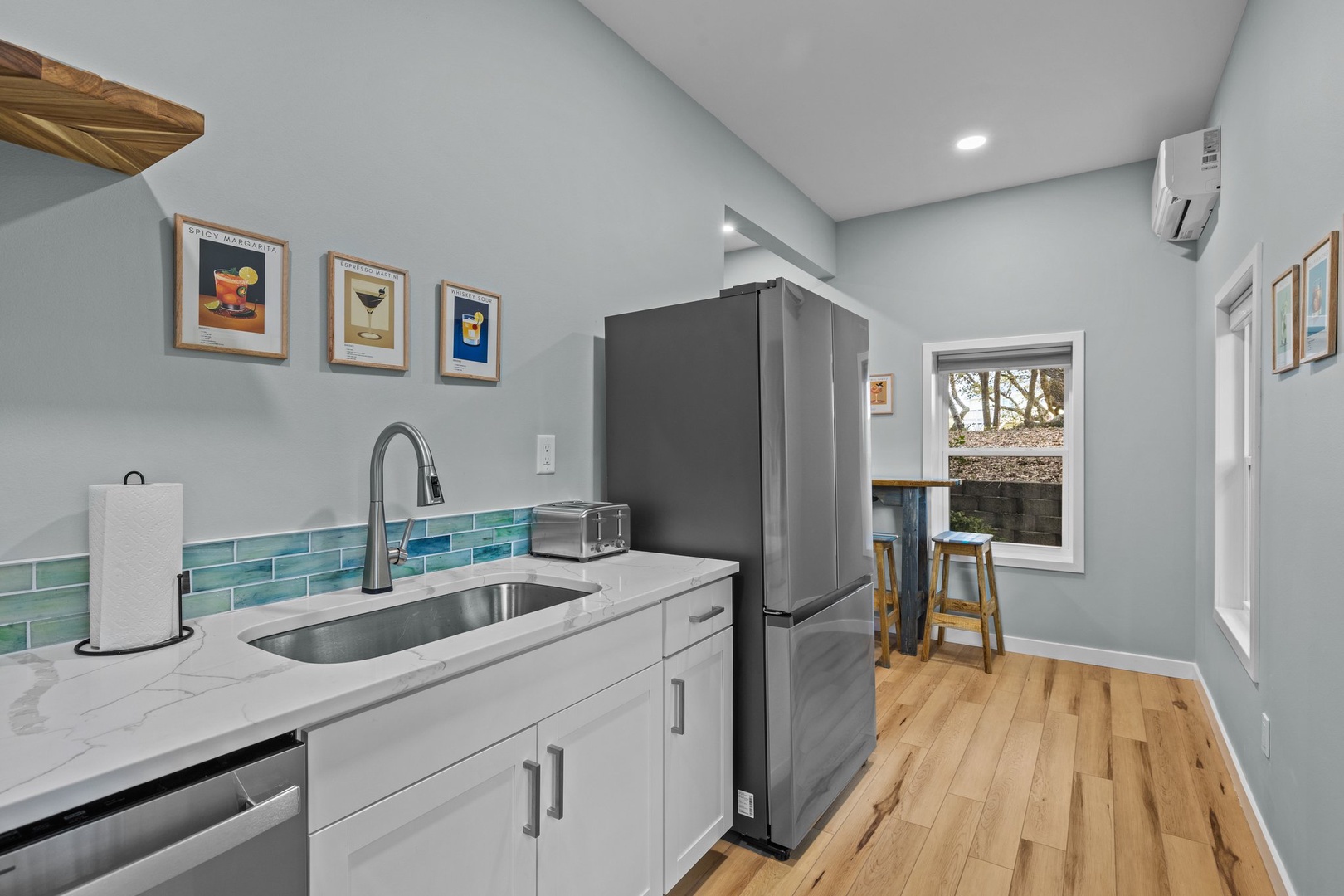 Step into your bright, modern kitchen where meal prep becomes a joy with sleek counters and charming blue tile details.