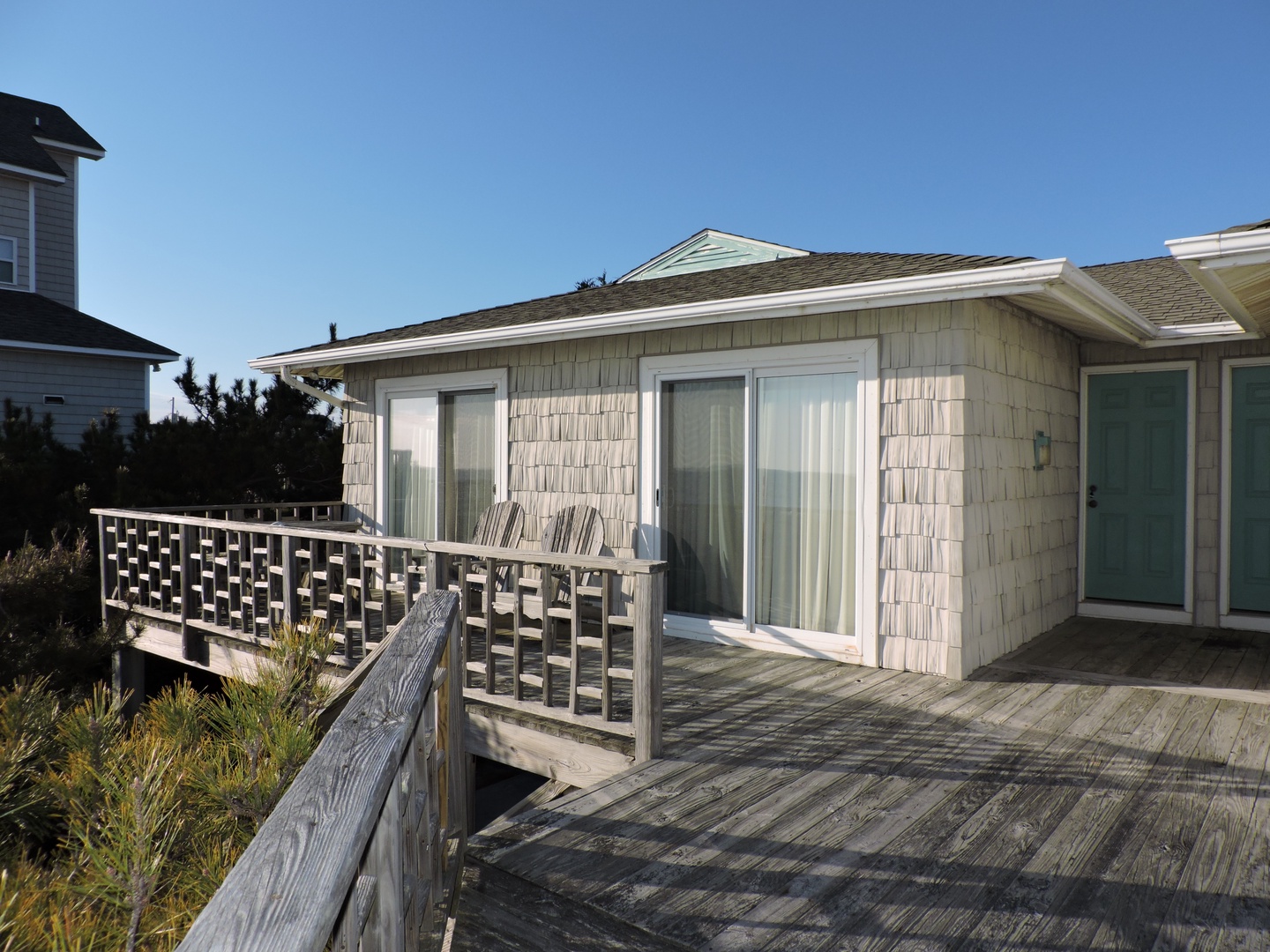 Charming coastal retreat with weathered shingle exterior and spacious wooden deck overlooking natural dune vegetation.