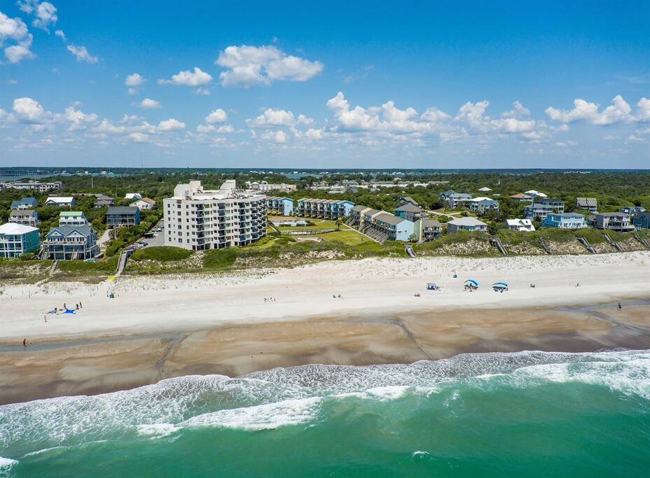 Stunning beachfront property complex positioned directly on pristine sandy shores with turquoise waters and gentle waves.