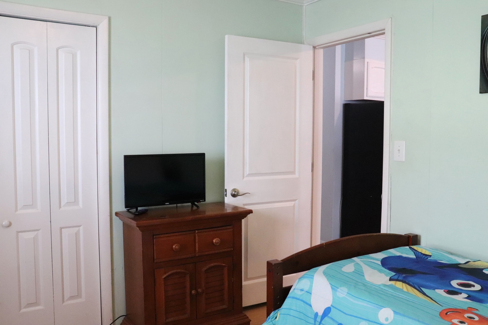 Your cozy bedroom features a flat-screen TV, charming wooden furniture, and plenty of wardrobe space for all your belongings during your stay.