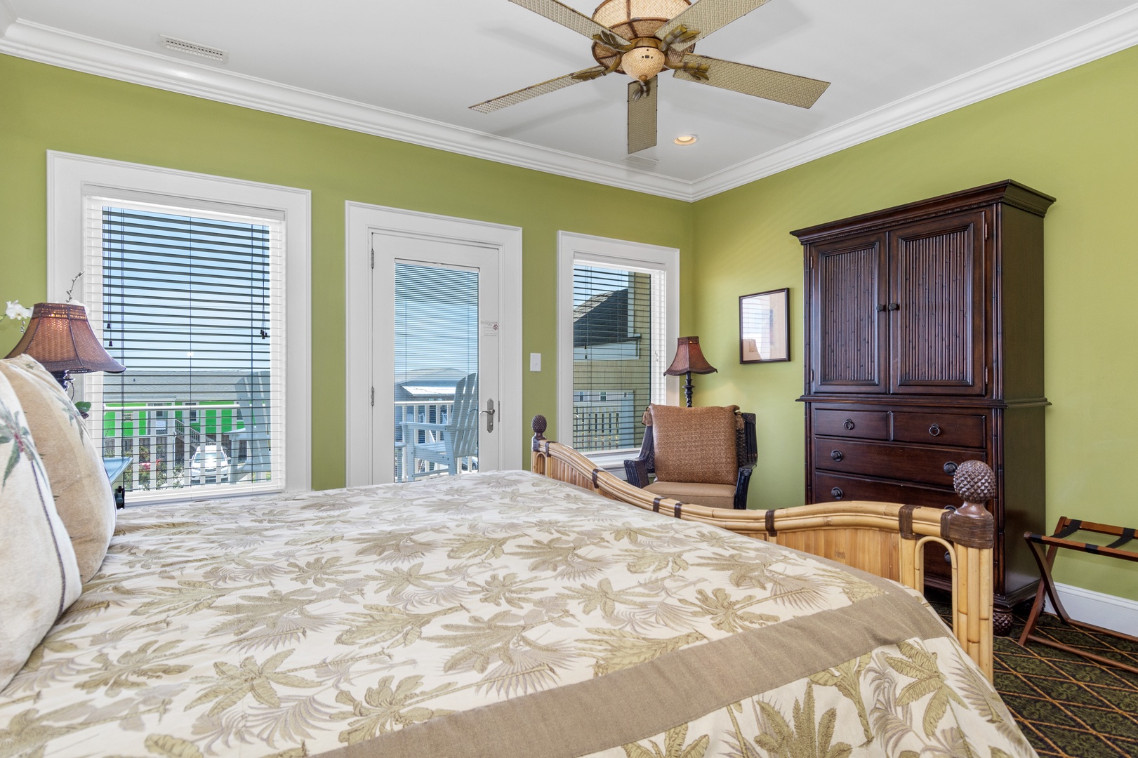 Unwind in your tropical-themed bedroom featuring a plush bed, ceiling fan, and private balcony access for ultimate relaxation.