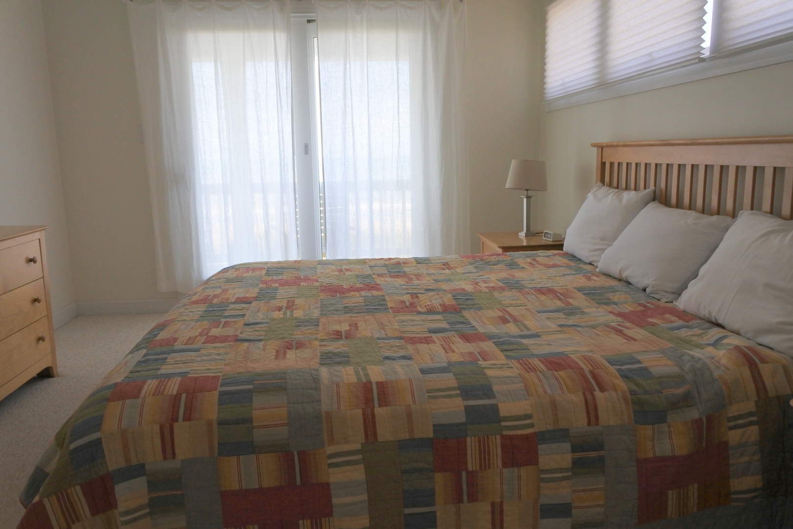 Sink into comfort in this peaceful bedroom with natural light streaming through sheer curtains and cozy bedding.
