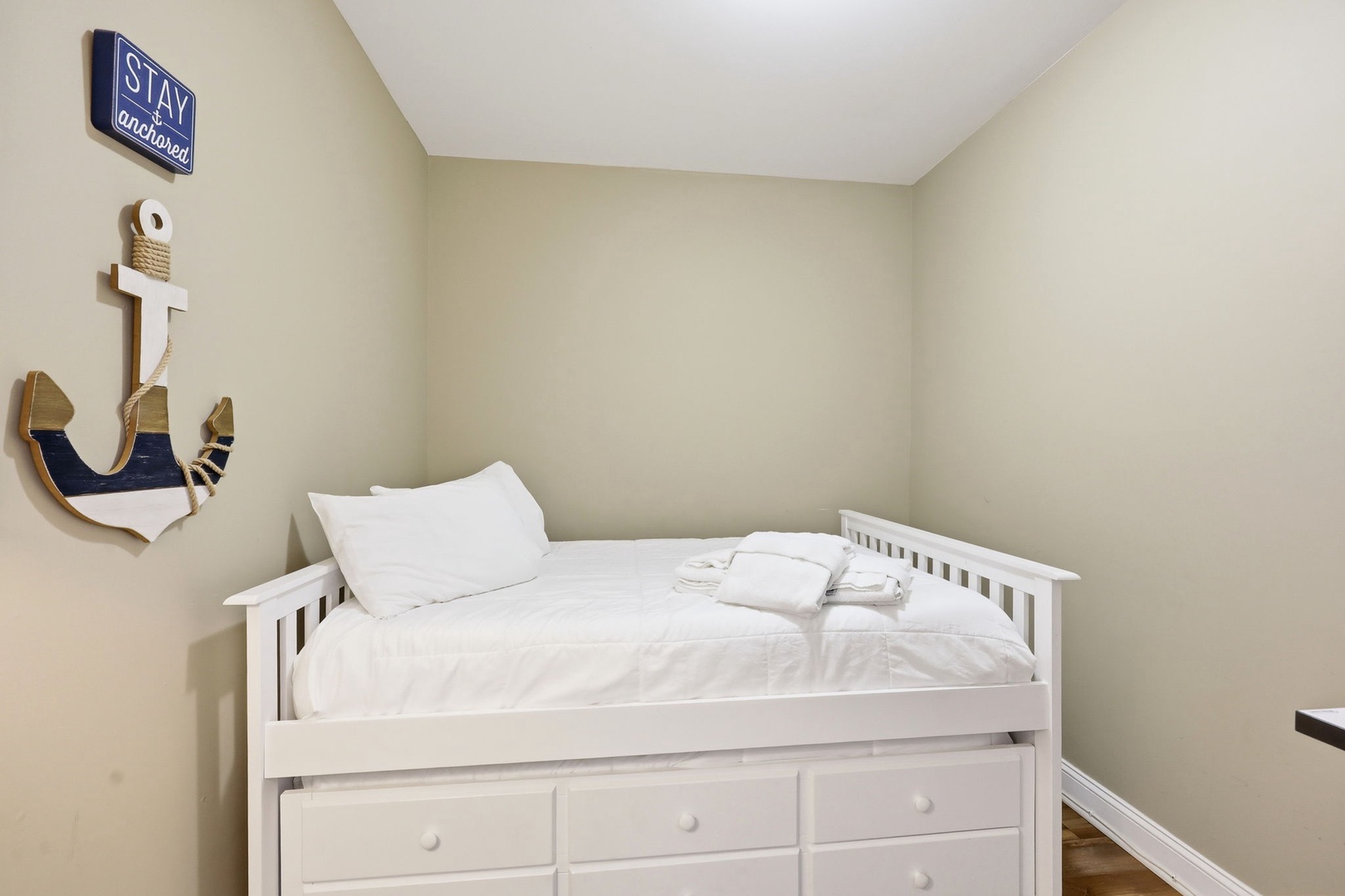 Cozy up in this nautical-themed bedroom with its crisp white linens and built-in storage drawers. The playful anchor decor adds coastal charm to your restful retreat.
