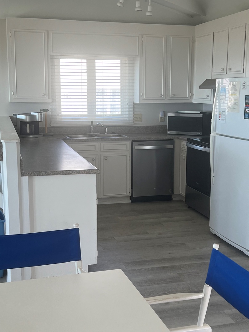 Your fully equipped kitchen features granite counters, stainless appliances, and bright white cabinetry perfect for preparing meals during your stay.