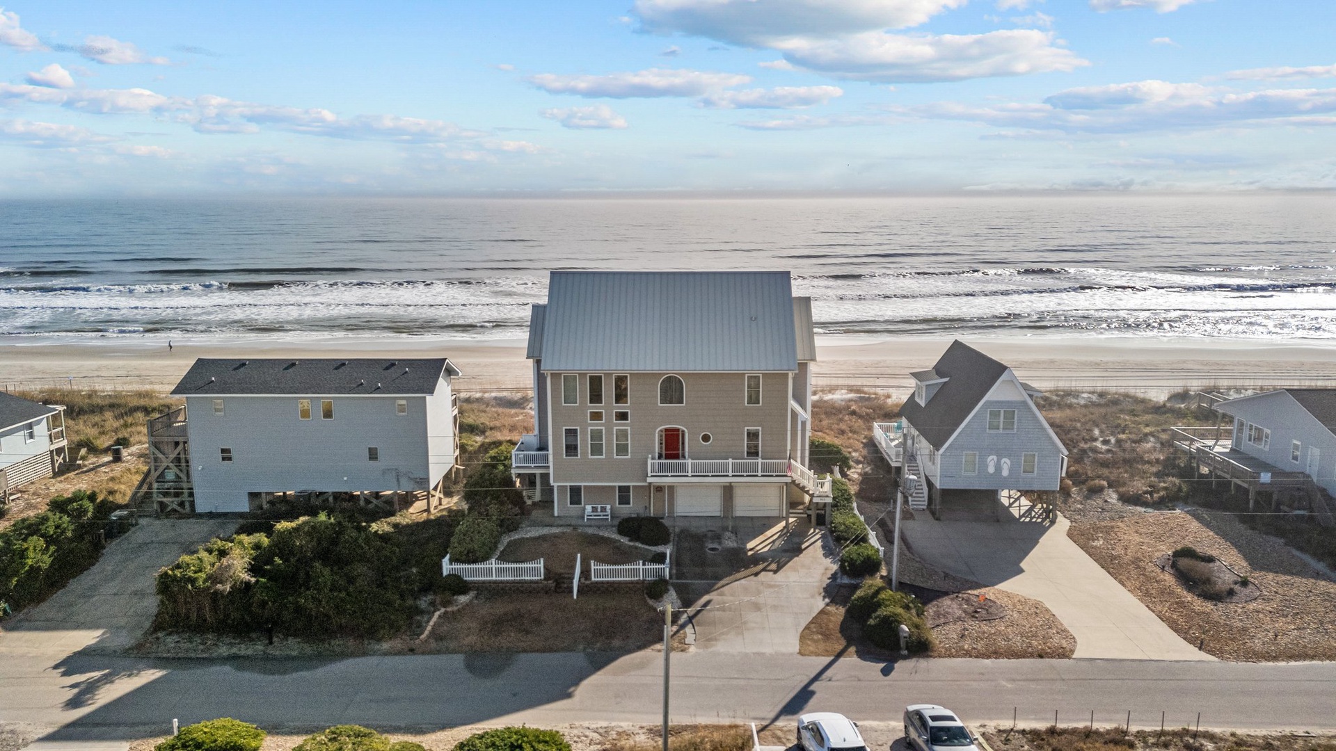 Oceanfront vacation homes positioned directly along pristine sandy beach with rolling waves and expansive coastal views.