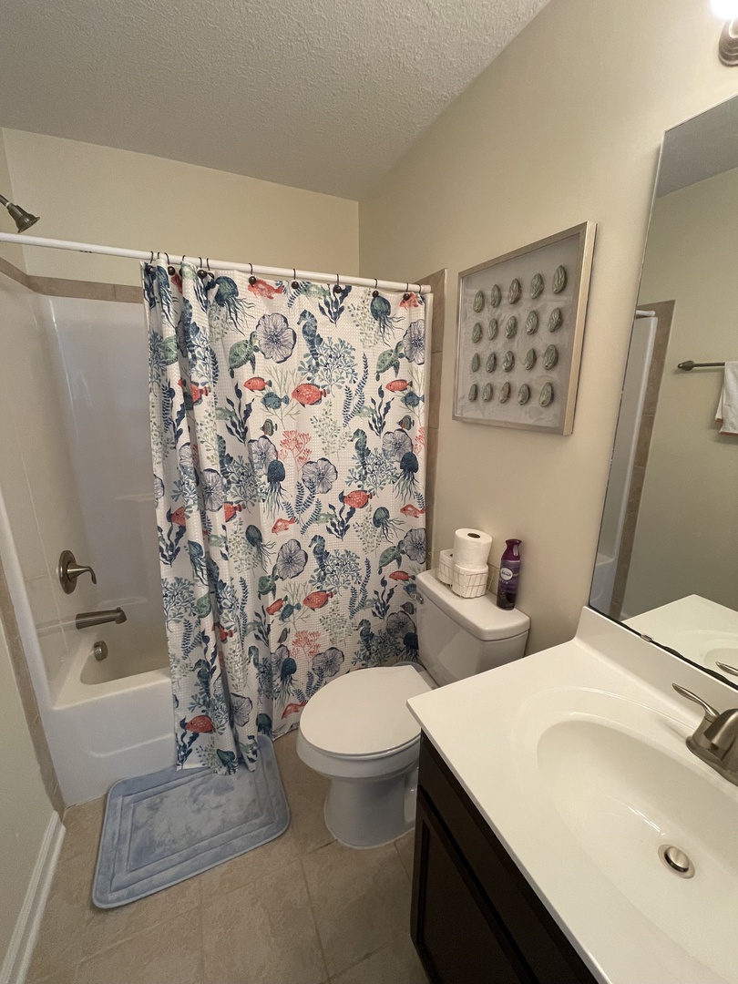 Your private bathroom features a modern shower, toilet, and charming floral curtain that adds a cheerful touch to your daily routine.